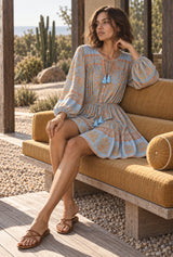 Apricot Sky light blue floral mini dress, seated editorial view with AI-generated adult model