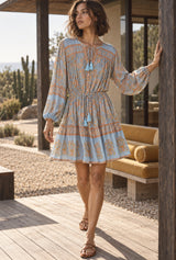 Apricot Sky light blue floral mini dress on an AI-generated adult model at a timber coastal house