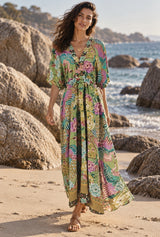 Peacock Green Gold maxi dress on a model by the coast — AI-generated editorial image