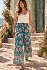 Woman walking in Meadow Green floral wide leg pants, relaxed bohemian fashion editorial