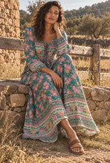 Emerald Wildflower green floral maxi dress, seated editorial view with AI-generated adult model