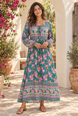 Emerald Wildflower green floral maxi dress styled on an AI-generated adult model in a sunlit bohemian courtyard
