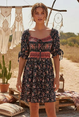 Dark floral mini dress with patterned bodice, short tie-detail sleeves and flowing skirt