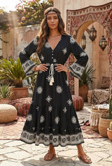 Black floral maxi dress with V-neck, long bell sleeves, white tassels and patterned ruffle hem